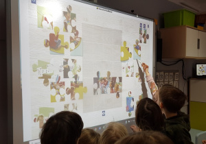 Dziewczynka układa puzzle na tablicy interaktywnej
